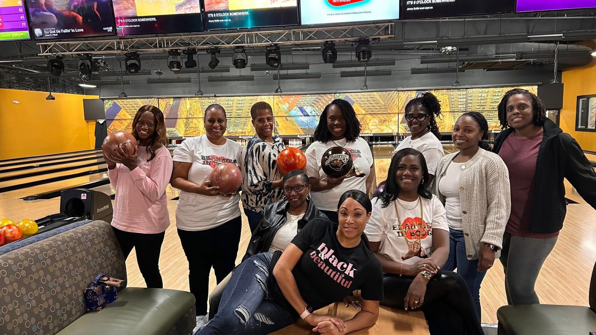 Sisterhood bowling night — members posing with bowling balls at the lanes