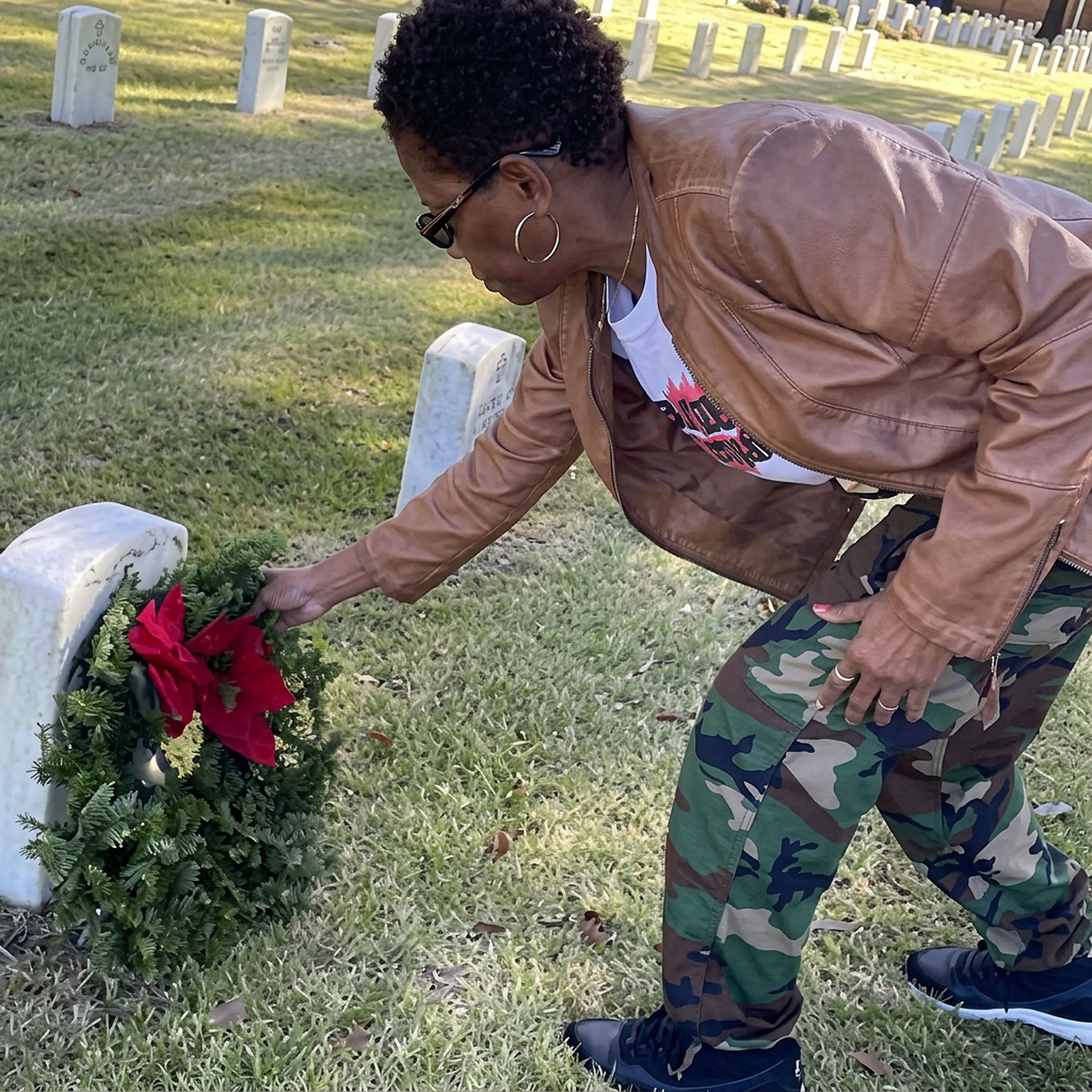 Member placing a holiday wreath at a veteran's headstone