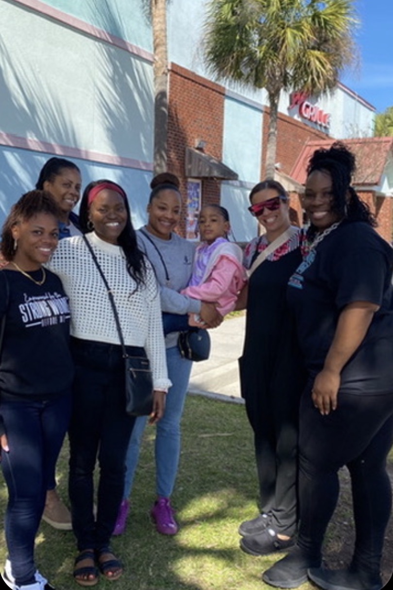 Captain Nathacha Rock with sisters at a community gathering